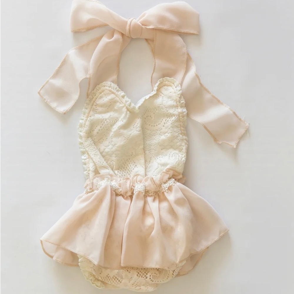 This is a lovely lace baby romper. Ruffle and bow detail and ties in the back.